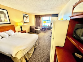 Una habitación de hotel con una cama, un escritorio, una silla, un televisor y una ventana con cortinas.