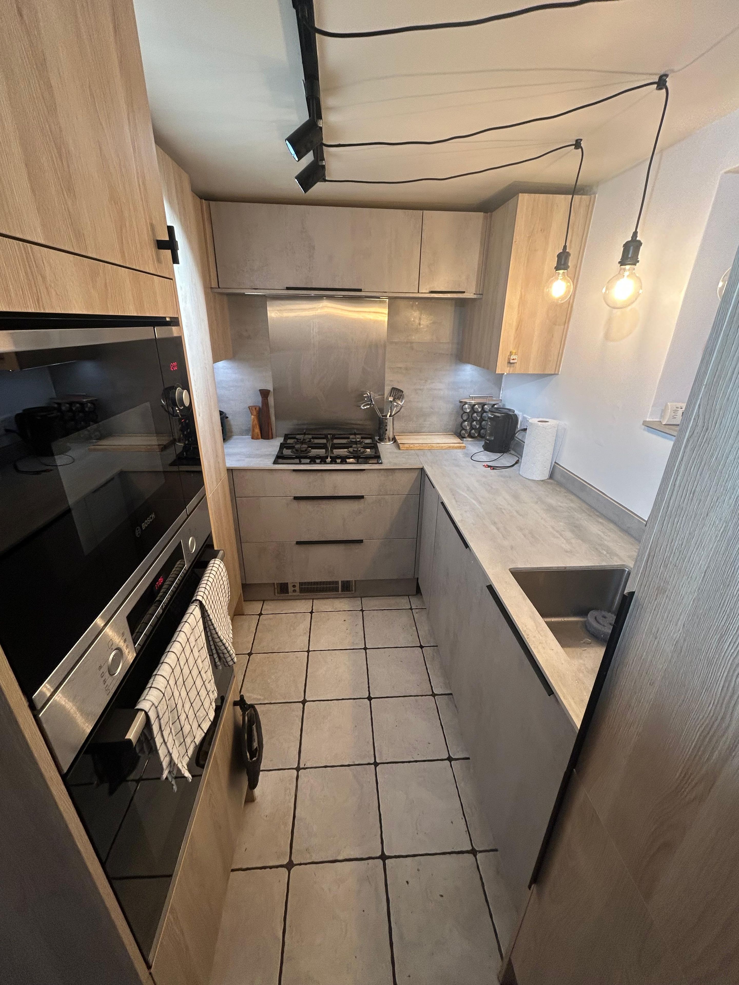 A compact kitchen with a built-in oven, a stove, and a sink.
