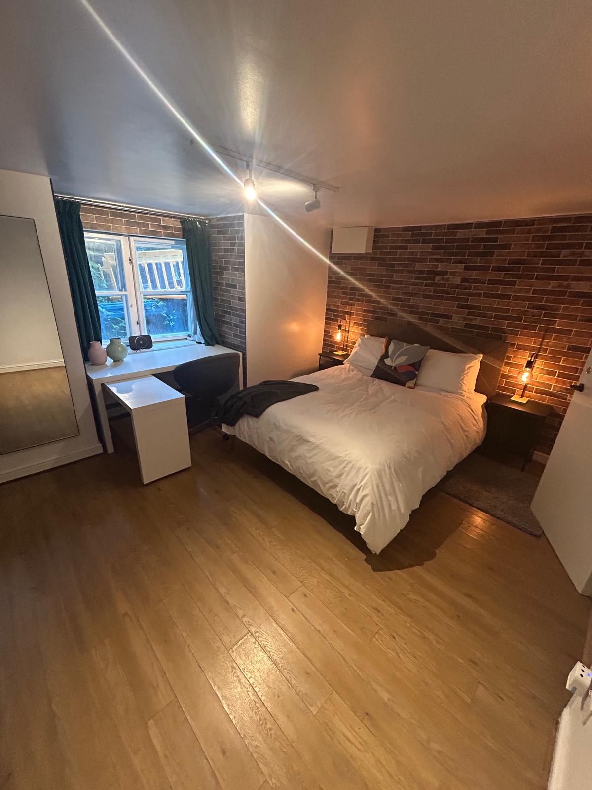 Een slaapkamer met een bed, een bureau en een raam.