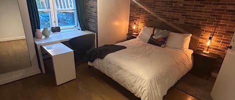 Een slaapkamer met een bed, een bureau en een raam.