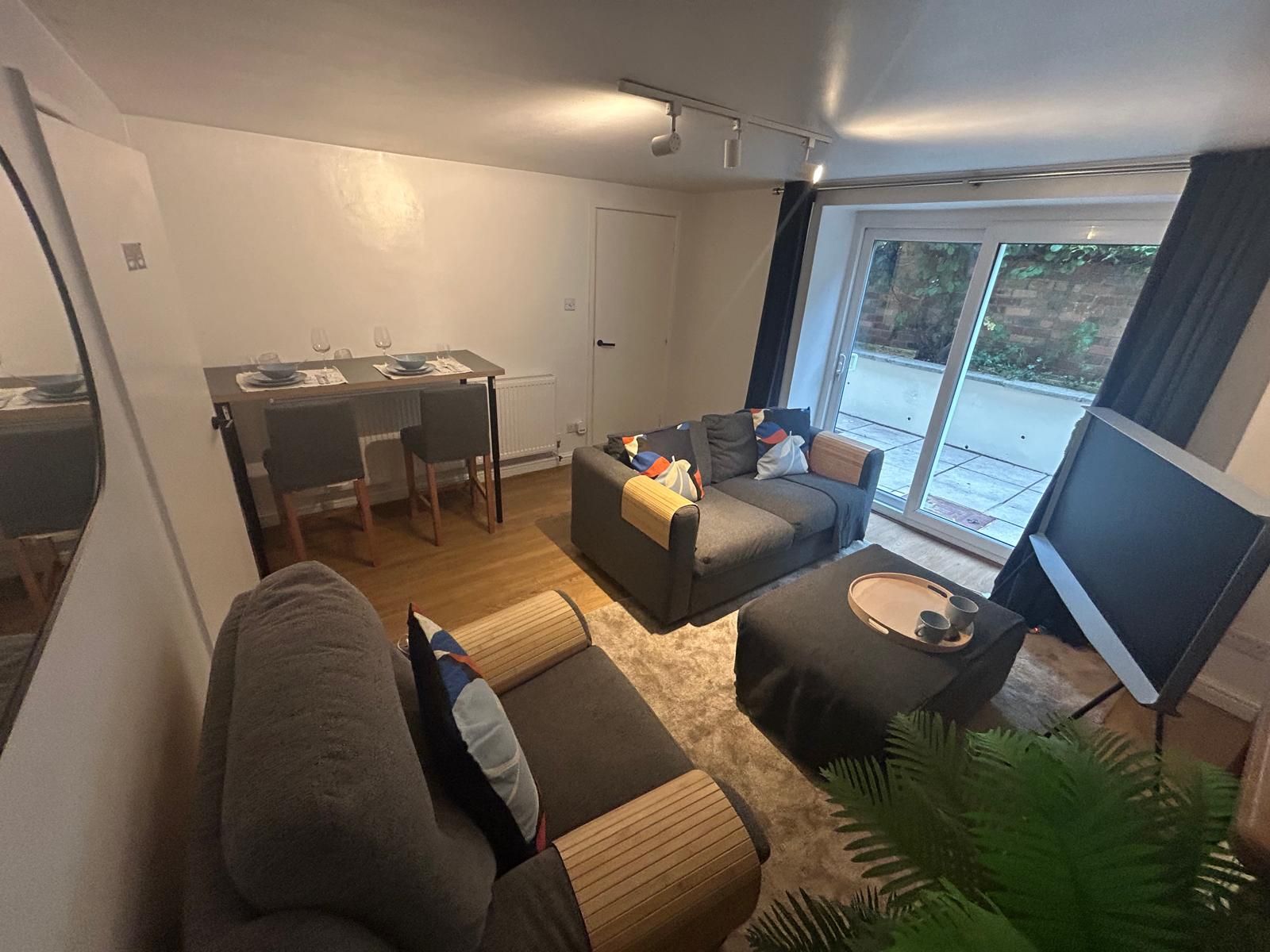 Een moderne woonkamer met een bank, een eettafel met stoelen en een groot raam met uitzicht.