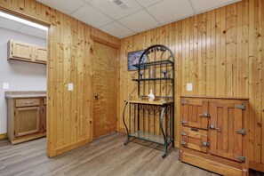 Une pièce aux murs recouverts de panneaux de bois, avec une étagère en métal, des armoires en bois et une porte.