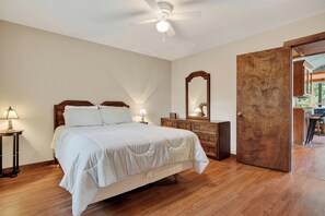 Ein Schlafzimmer mit einem Bett, einem Schminktisch, einem Spiegel und einem Deckenventilator.