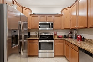 A kitchen with stainless steel appliances, wooden cabinets, granite countertops, and a red coffee maker. - ⚓Waterview-Resort Style Amenities-Bikes & More⚓ (Bradenton)