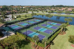 A tennis court complex with multiple courts, surrounded by greenery and a body of water. - ⚓Waterview-Resort Style Amenities-Bikes & More⚓ (Bradenton)