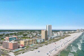 A coastal cityscape with a beachfront, high-rise buildings, and a clear sky. - Buena Vista 201 - Gulf-Front 3BR, Balcony Over the Pool - Beachball Properties (Gulf Shores)