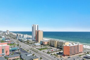 Un paysage urbain côtier avec un hôtel imposant, un ciel dégagé et une plage en arrière-plan.