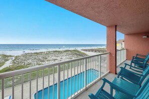 A balcony with a view of the beach and ocean, a pool, and blue chairs. - Gulf Front | Pool | Walk to Gulf Shores Favorites | BEACHBALL PROPERTIES (Gulf Shores)