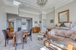 A spacious living room with a dining area, a fireplace, and a large mirror. - Appartement Bleu Panorama - Welkeys (Bandol)