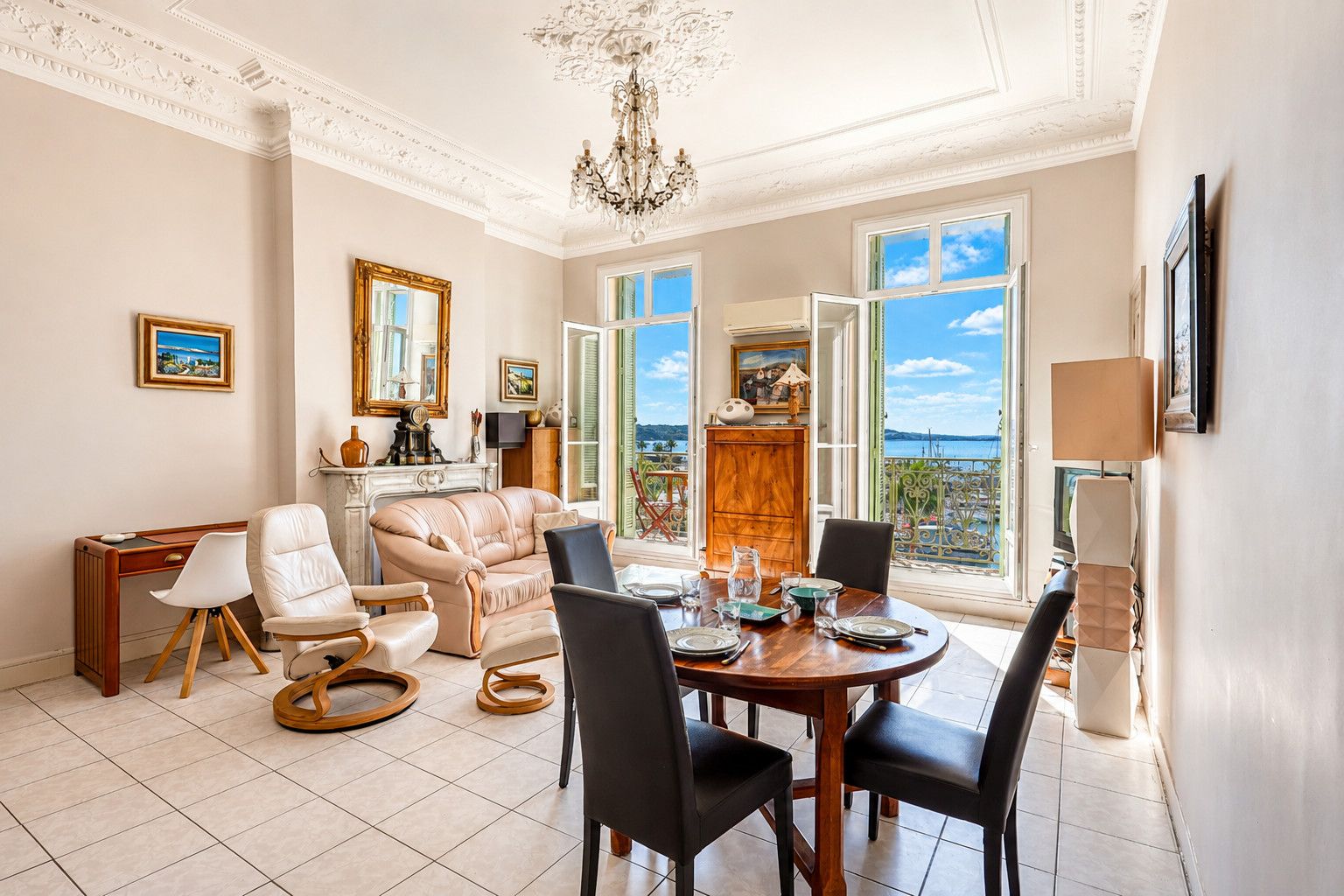 Amplia sala de estar con comedor, ventanas grandes con vista y un candelabro.