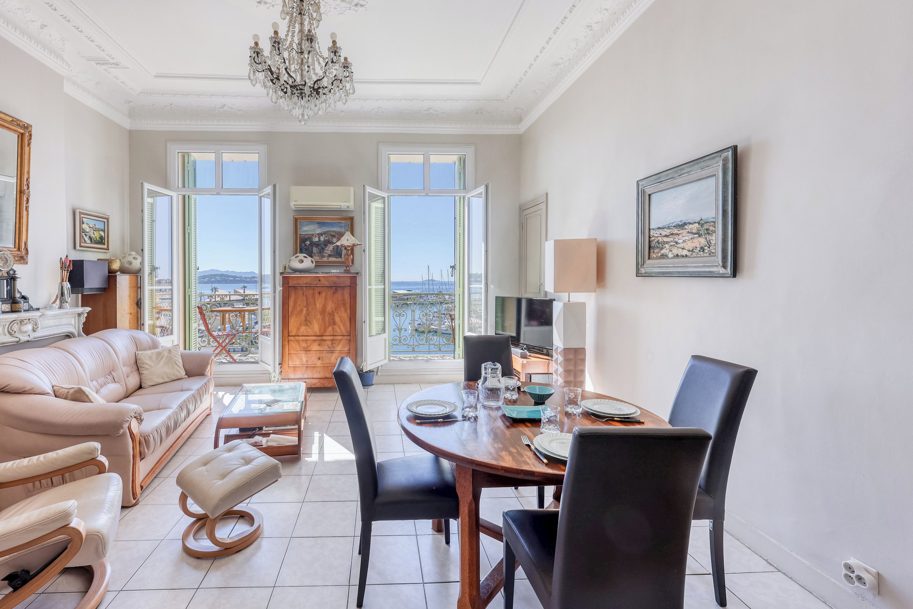 Un salon spacieux avec un canapé, un pouf et un coin repas comprenant des chaises et une table.