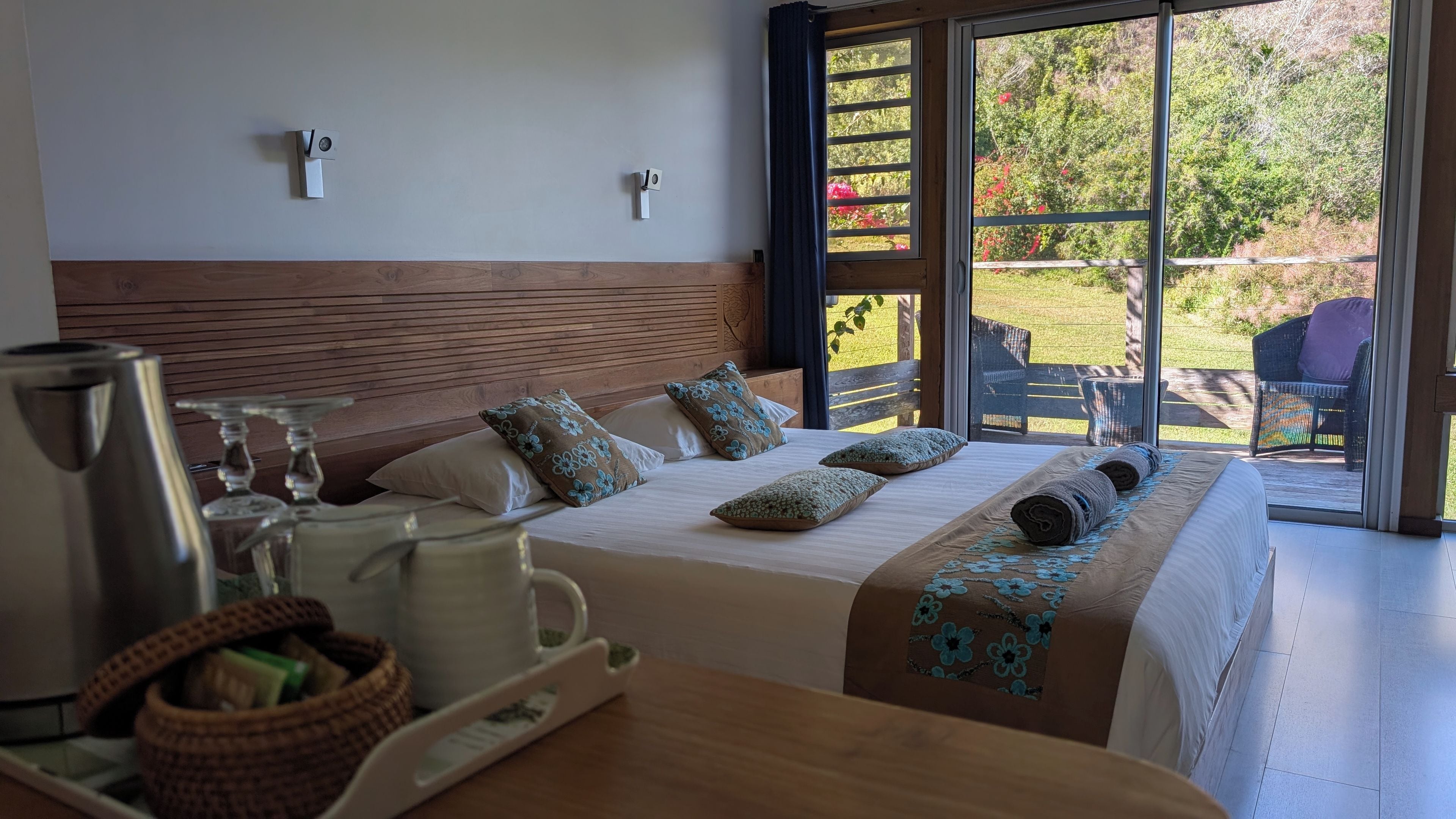 Quarto de hotel com uma cama, uma mesa com chaleira e vista para o exterior.