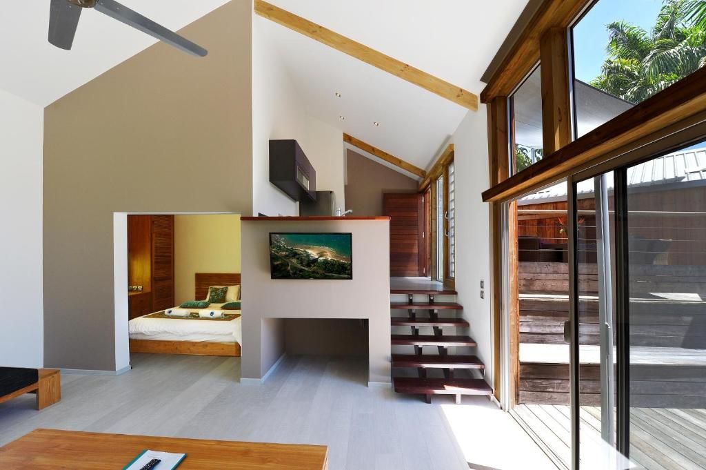Un intérieur moderne avec un escalier menant à un balcon, un lit et un tableau accroché au mur.