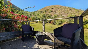 An outdoor patio with wicker furniture and a view of a hilly landscape.