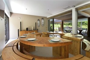 Un comedor circular de madera con varias mesas, cada una dispuesta con platos y copas de vino.