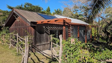 Um edifício rústico de madeira com telhado inclinado, painéis solares e cerca de madeira.