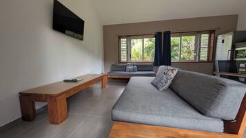 Ein Wohnzimmer mit einer Couch, einer Holzbank und einem an der Wand befestigten Fernseher.