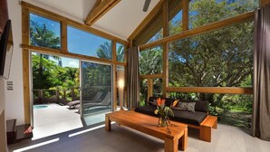 Um quarto espaçoso com grandes janelas, um banco de madeira e um sofá.