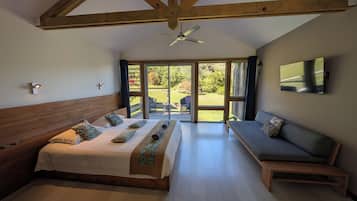 Quarto com cama, sofá, ventilador de teto e televisão.