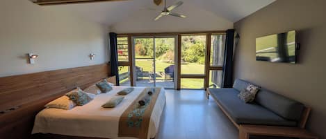 Un dormitorio con cama, sofá, ventilador de techo y televisor.