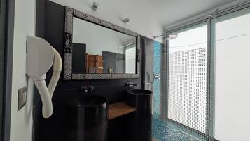 Ein modernes Badezimmer mit einem schwarzen Waschbecken, einem Spiegel mit dekorativem Rahmen und einer Duschkabine mit Glastür.