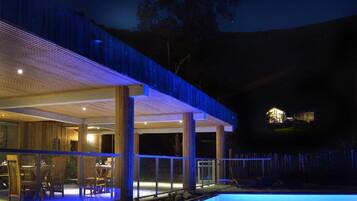 Ein modernes Haus mit Pool, großen Fenstern und einer überdachten Terrasse.