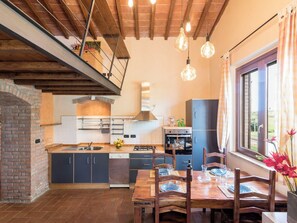 Eine Küche mit Backofen, einem Essbereich mit Tisch und Stühlen sowie einem Fenster mit Vorhängen.