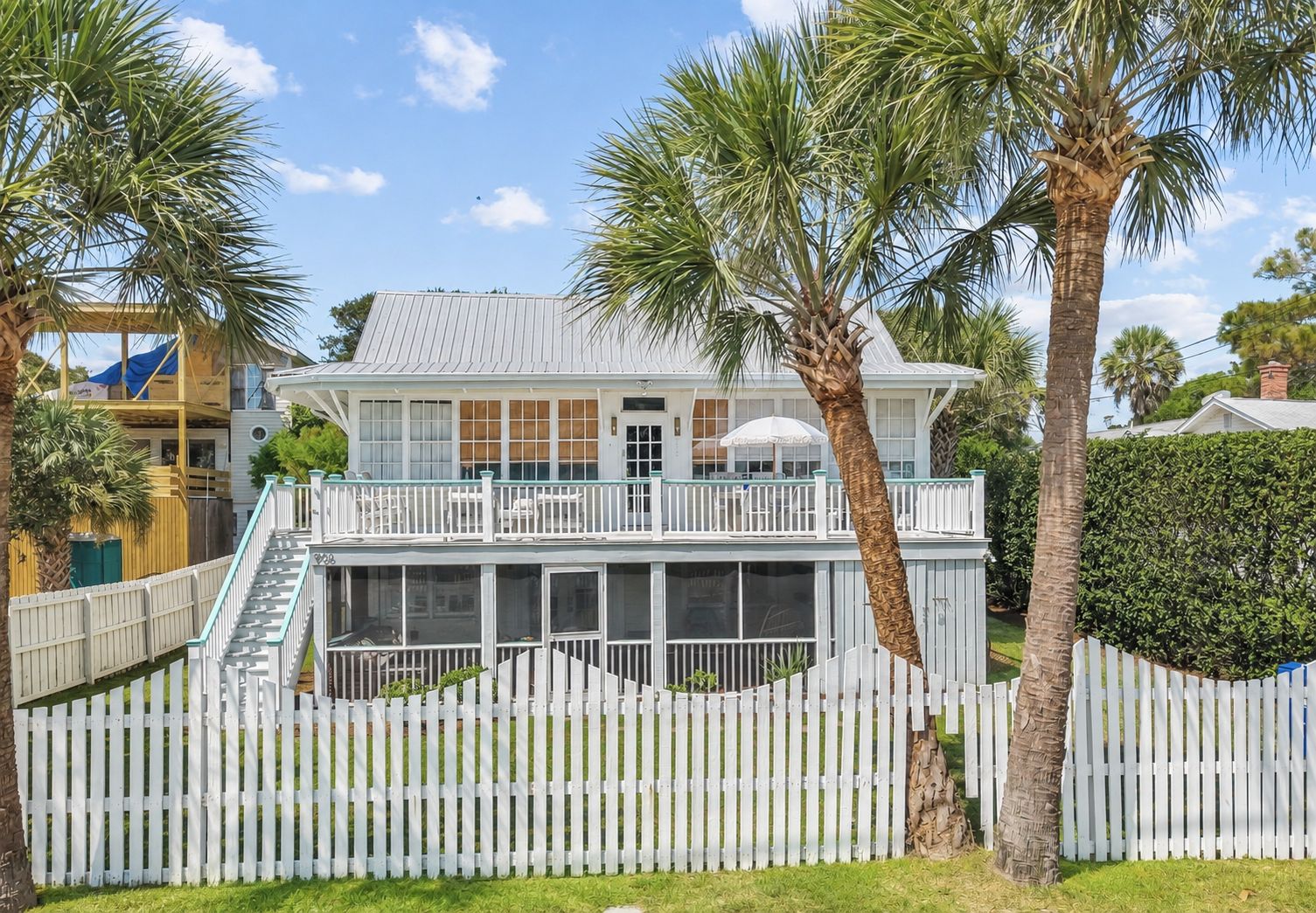 A two-story house with a balcony, a covered porch, and a white picket fence.