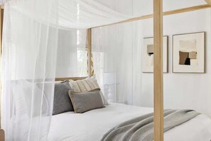 Un letto con baldacchino, cuscini e coperta.