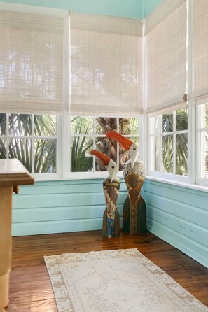 A room with a wooden floor, a patterned rug, and two bird sculptures. - Beachside Bliss | 4BR (plus a bonus bedroom)  Folly Beach Home Steps from Beach Access (Folly Beach)