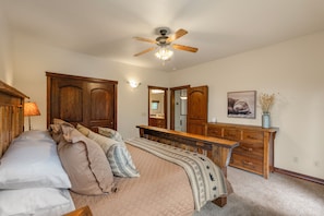 Een slaapkamer met een bed, een houten dressoir en een plafondventilator.