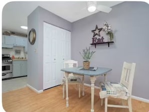 A dining area with a table and chairs, a wall-mounted shelf with a star decoration, and a door leading to a kitchen. - Graceful Stays: Cozy Highlands 1BR – Unit 6 (Louisville)
