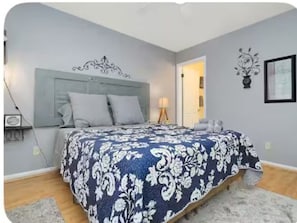 A bedroom with a bed, a nightstand, a lamp, and a wall decoration. - Graceful Stays: Cozy Highlands 1BR – Unit 6 (Louisville)
