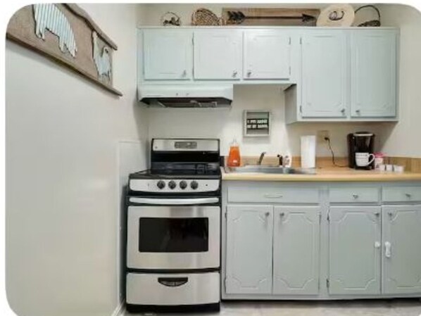 A kitchen with a double oven, light blue cabinets, and a wooden shelf above the counter. - Graceful Stays: Cozy Highlands 1BR – Unit 6 (Louisville)