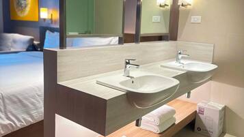 A hotel bathroom with a double sink, a large mirror, and a towel rack.