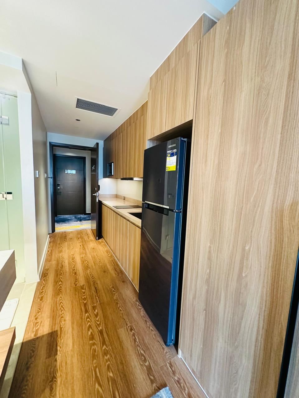 A modern kitchen with wooden cabinetry and a black refrigerator.