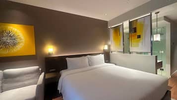 A hotel room with a bed, two bedside tables, a chair, a large mirror, and a wall art piece.