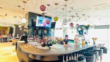 A bar area with a round counter, stools, and a variety of bottles.