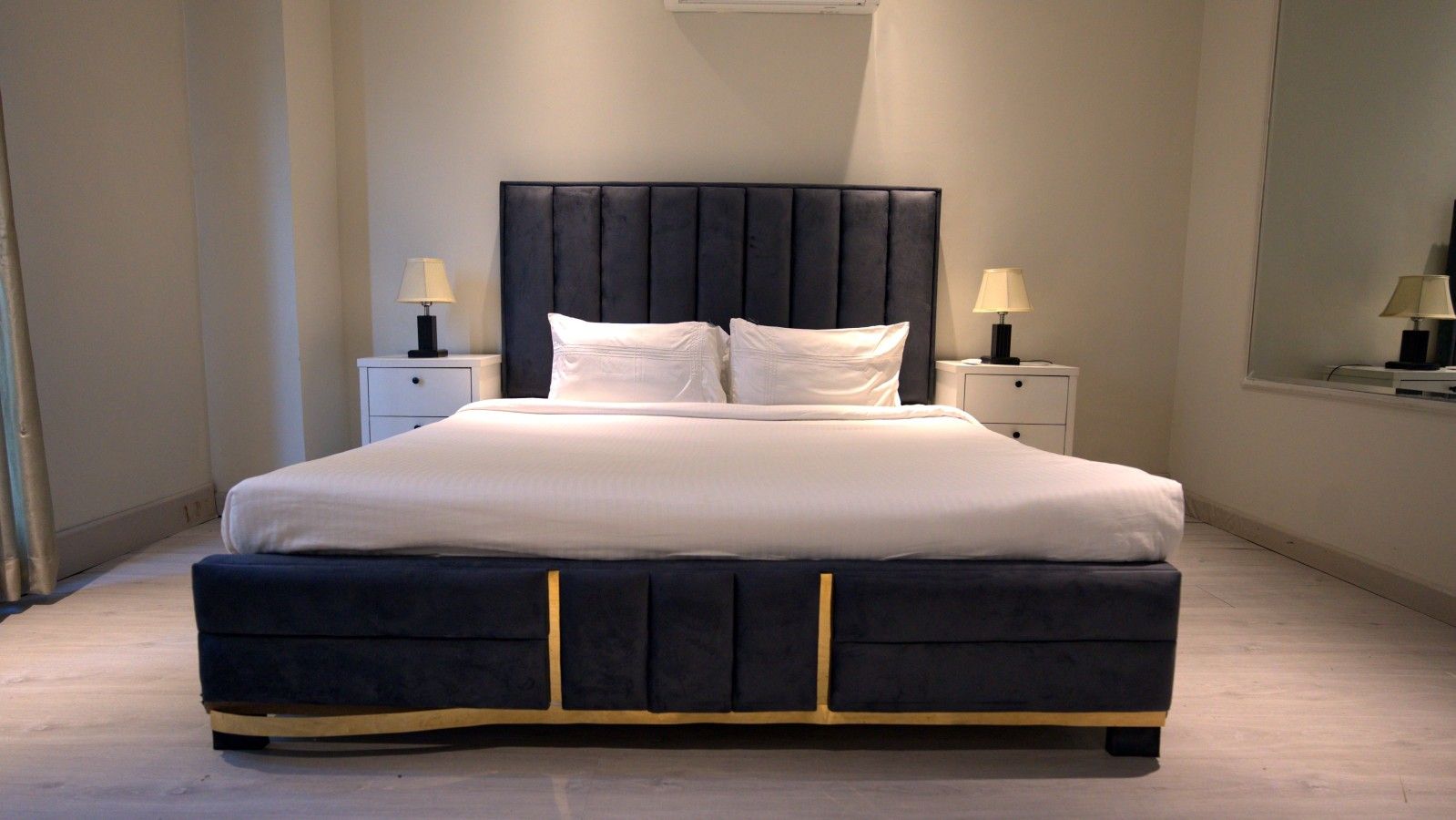 A modern bedroom with a large bed, two bedside tables, and a headboard.
