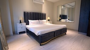 Ein modernes Schlafzimmer mit einem großen Bett, Nachttischen, einem Spiegel und einer Klimaanlage.