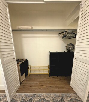 Ein begehbarer Kleiderschrank mit Holzboden, einem schwarzen Kommoden und einer Kleiderstange.