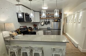 A modern kitchen with a central island, bar stools, pendant lighting, and stainless steel appliances. - 1BR/1BA in Andersonville · pet-friendly · workspace · garage parking · king bed (Chicago)