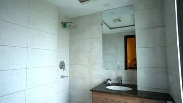 A bathroom with a shower, a sink with a mirror, and a wooden vanity.