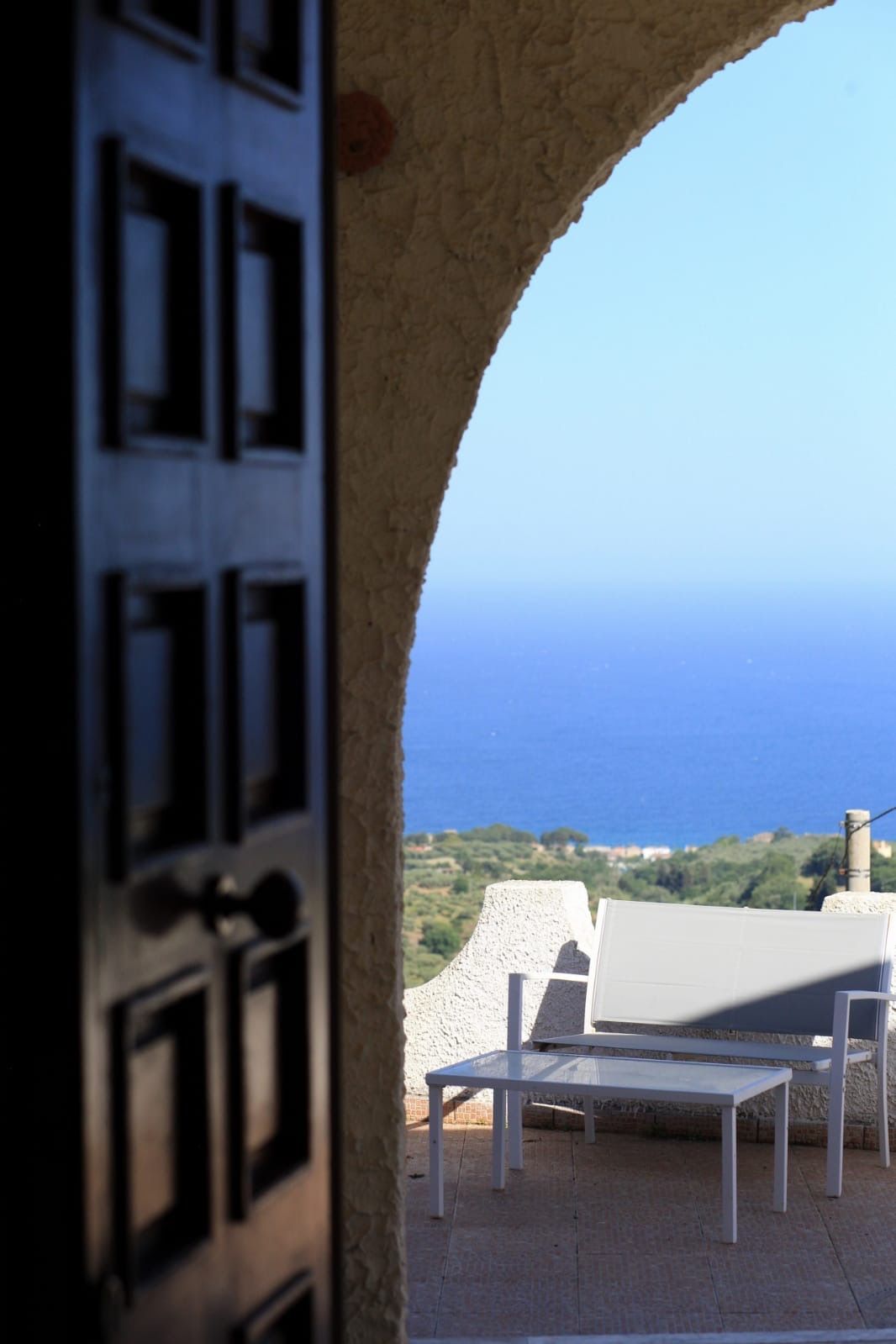 Une porte donnant sur un espace extérieur aménagé avec une vue sur la mer.