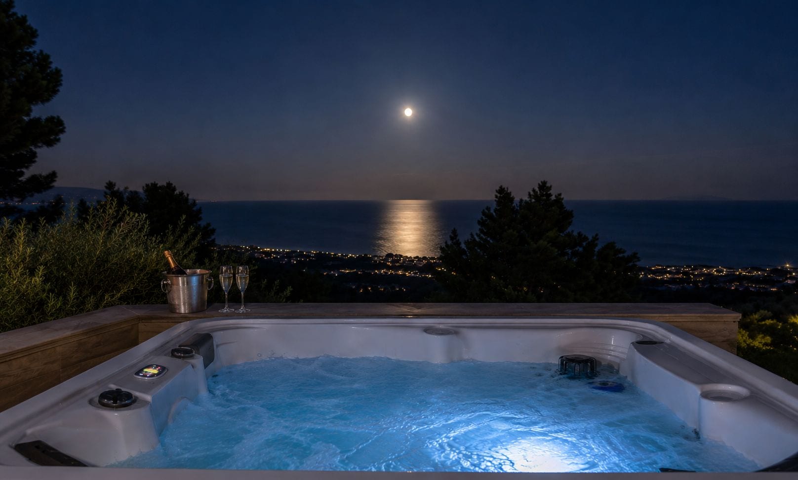 Jacuzzi amb vista al mar i les llums de la ciutat a la nit.