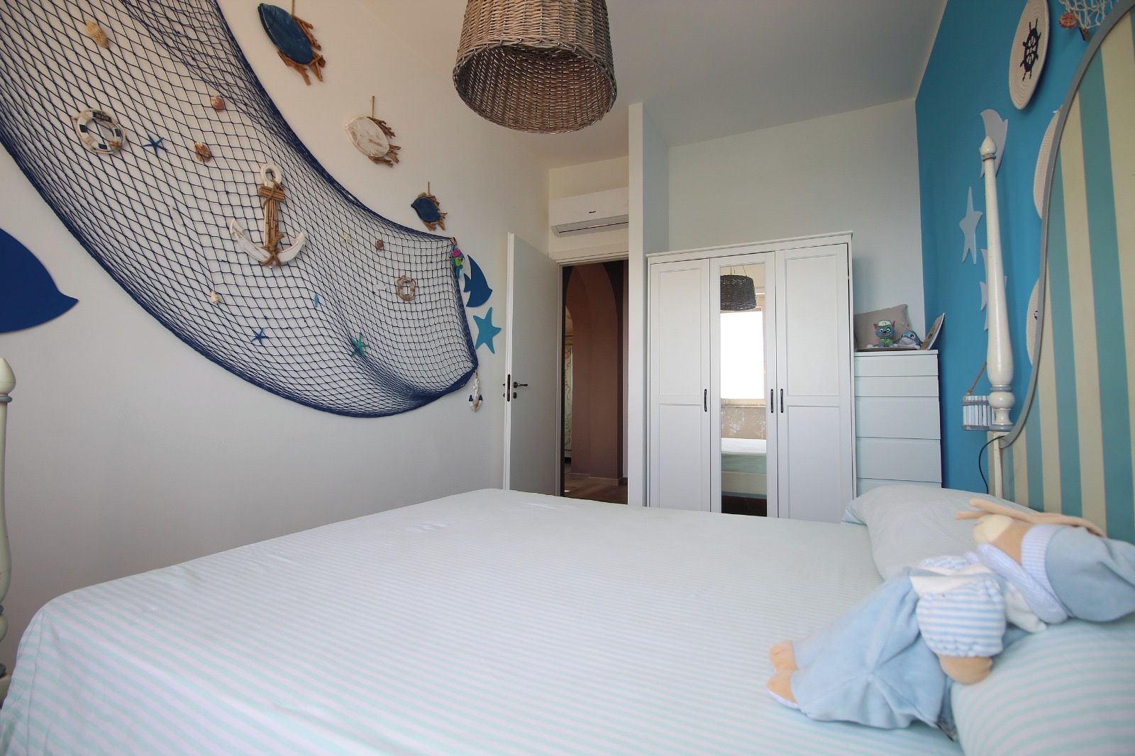 Ein Schlafzimmer mit einem großen Bett, einem Kleiderschrank und einer Wand, die mit maritimen Elementen dekoriert ist.
