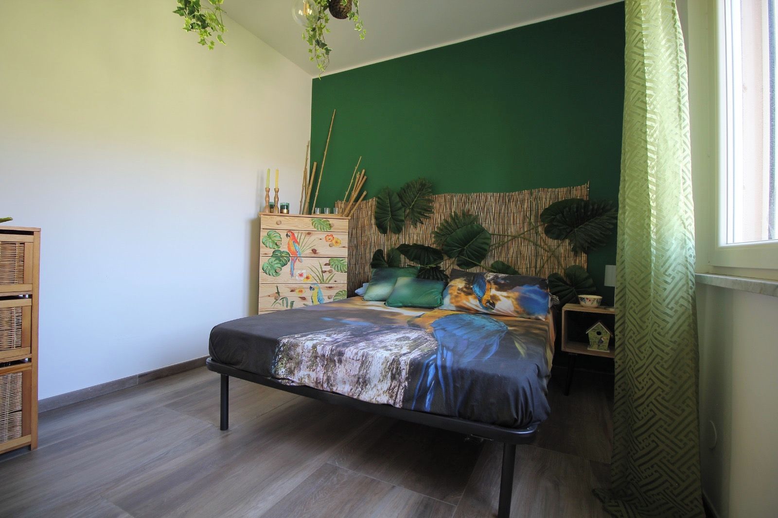 Un dormitorio con una cama, un aparador, una mesita de noche y una ventana con cortinas.