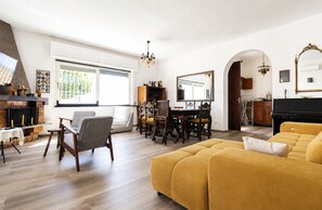 A spacious living room with a fireplace, a dining area, and a piano.