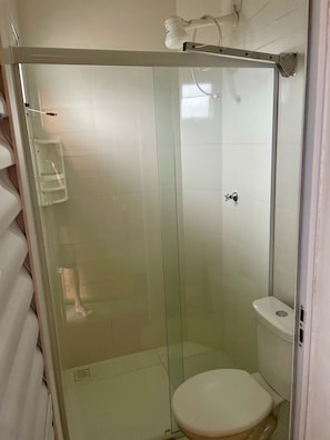 Een douchecabine met glazen wanden, een toilet en een handdoekhouder.