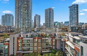 A high-rise residential building with multiple balconies, large windows, and a modern architectural design. - Bright 1.5 Bed w/Pool, Parking, HotTub, Sauna, Gym (Vancouver)